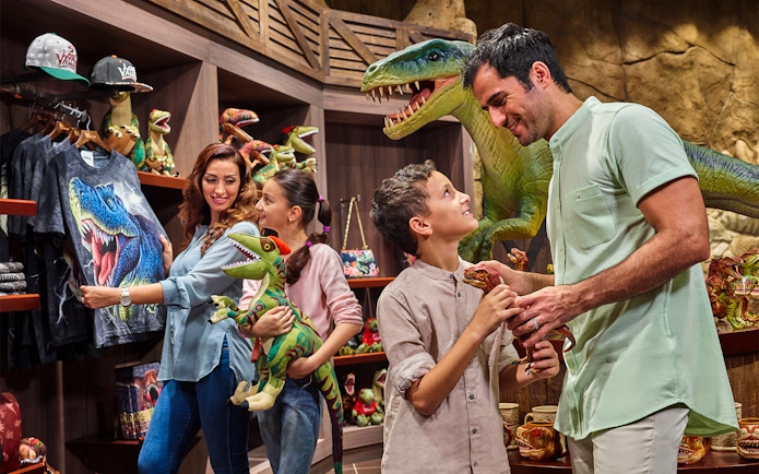Family shopping for dinosaur toys at IMG Worlds of Adventure gift shop.