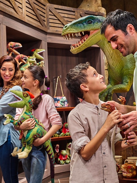 Family shopping for dinosaur toys at IMG Worlds of Adventure gift shop.