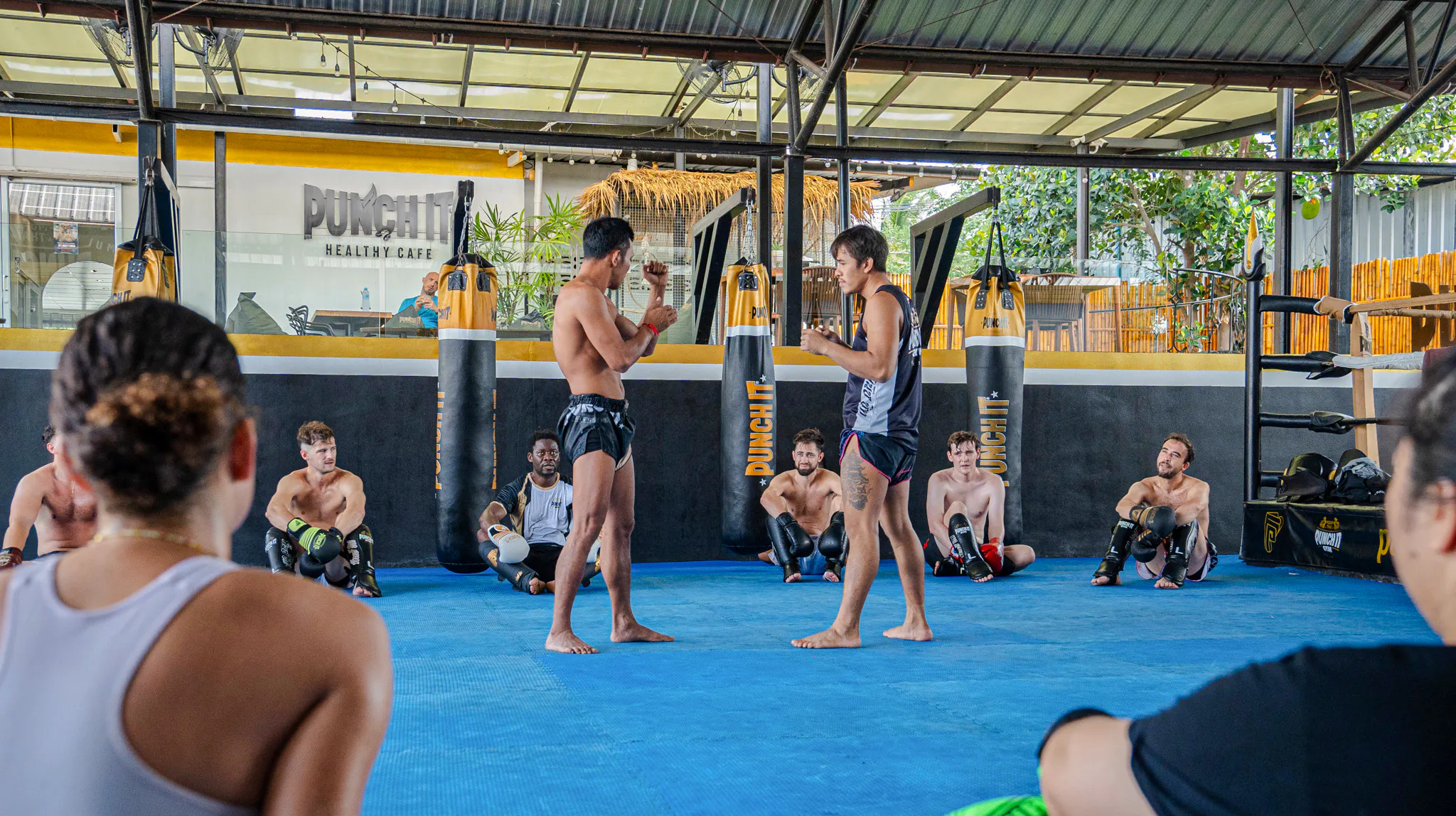 Muay Thai instructors demonstrating techniques to beginners in a Koh Samui boxing class.
