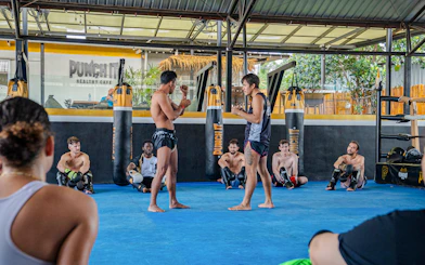 Muay Thai instructors demonstrating techniques to beginners in a Koh Samui boxing class.