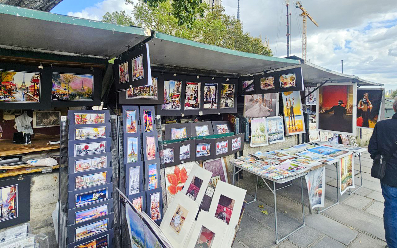 Outdoor art stalls near Notre Dame displaying colorful paintings and prints in Paris.
