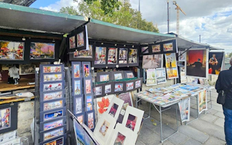 Outdoor art stalls near Notre Dame displaying colorful paintings and prints in Paris.