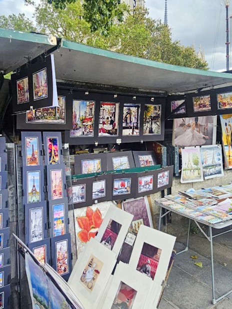 Outdoor art stalls near Notre Dame displaying colorful paintings and prints in Paris.