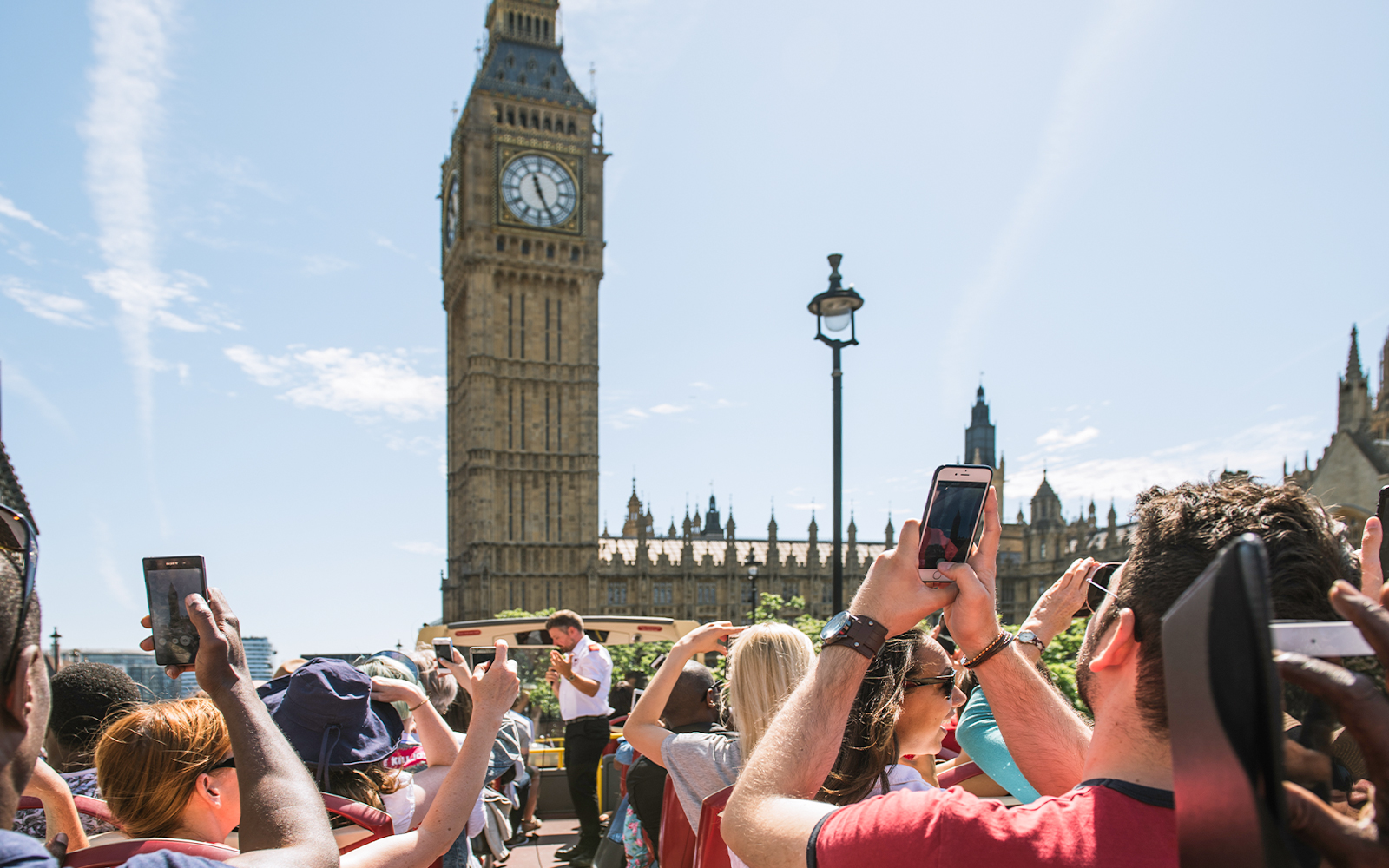 Tourists on HOHO bus taking photos of Big Ben, London.
