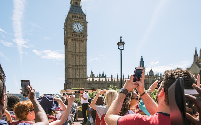 Tourists on HOHO bus taking photos of Big Ben, London.