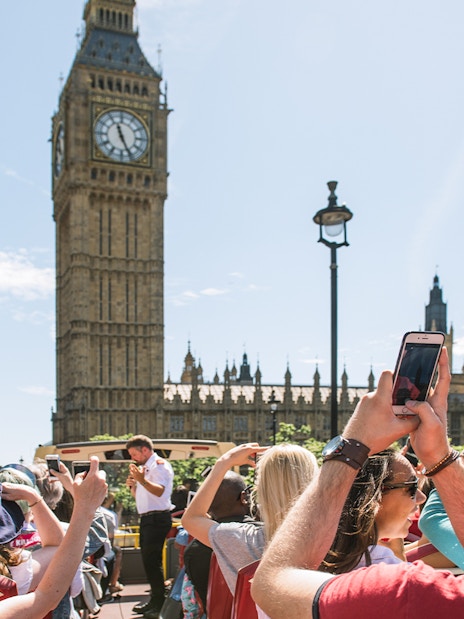 Tourists on HOHO bus taking photos of Big Ben, London.
