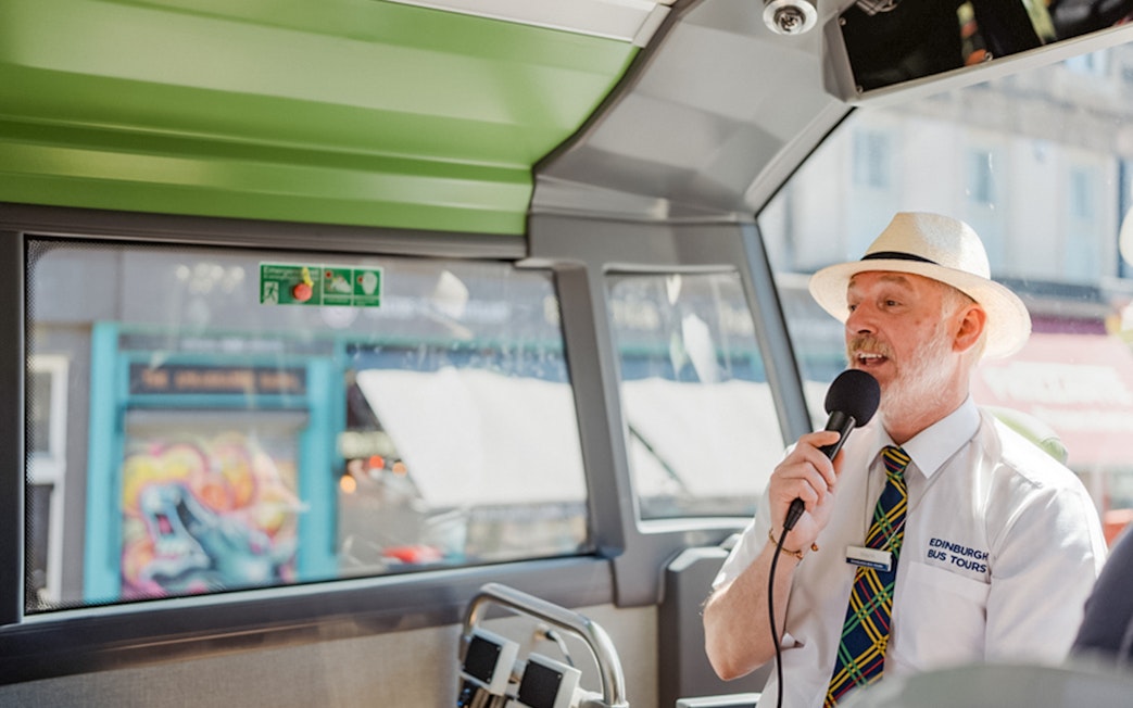 Guide speaking into a microphone on an Edinburgh HOHO bus tour.