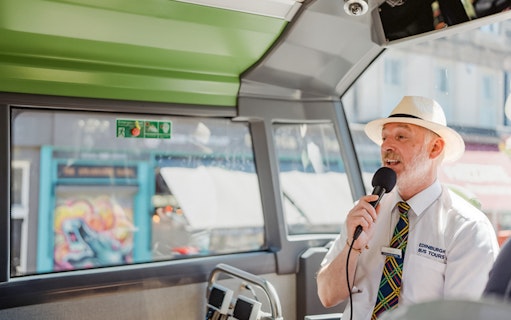 Guide speaking into a microphone on an Edinburgh HOHO bus tour.