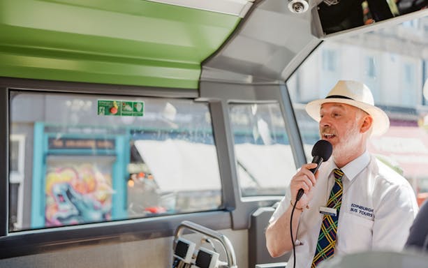 Guide speaking into a microphone on an Edinburgh HOHO bus tour.