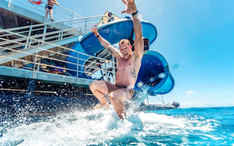 Tourist sliding into ocean from Sunlover waterslide at Moore Reef, Great Barrier Reef cruise.