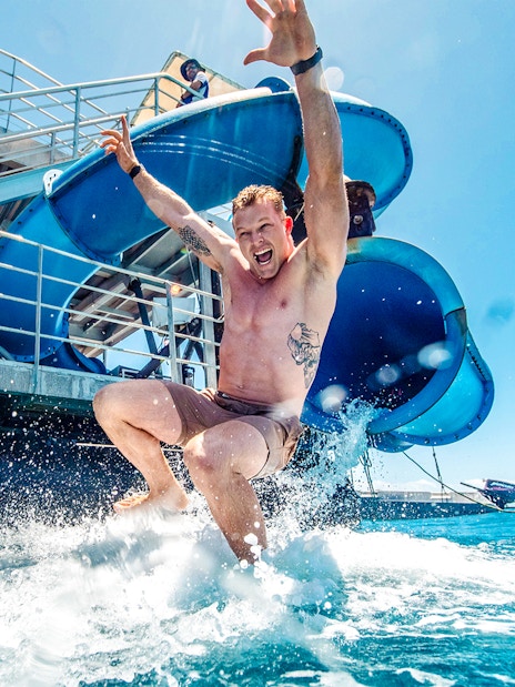 Tourist sliding into ocean from Sunlover waterslide at Moore Reef, Great Barrier Reef cruise.