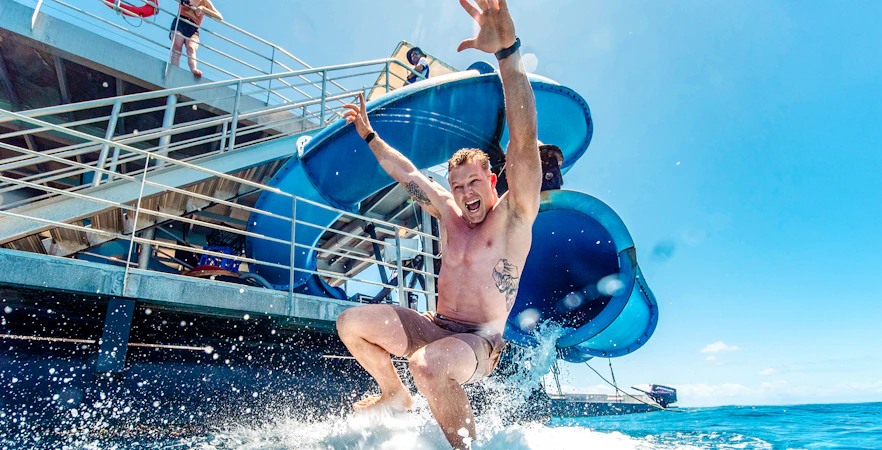 Tourist sliding into ocean from Sunlover waterslide at Moore Reef, Great Barrier Reef cruise.