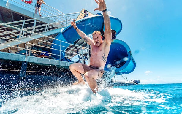 Tourist sliding into ocean from Sunlover waterslide at Moore Reef, Great Barrier Reef cruise.