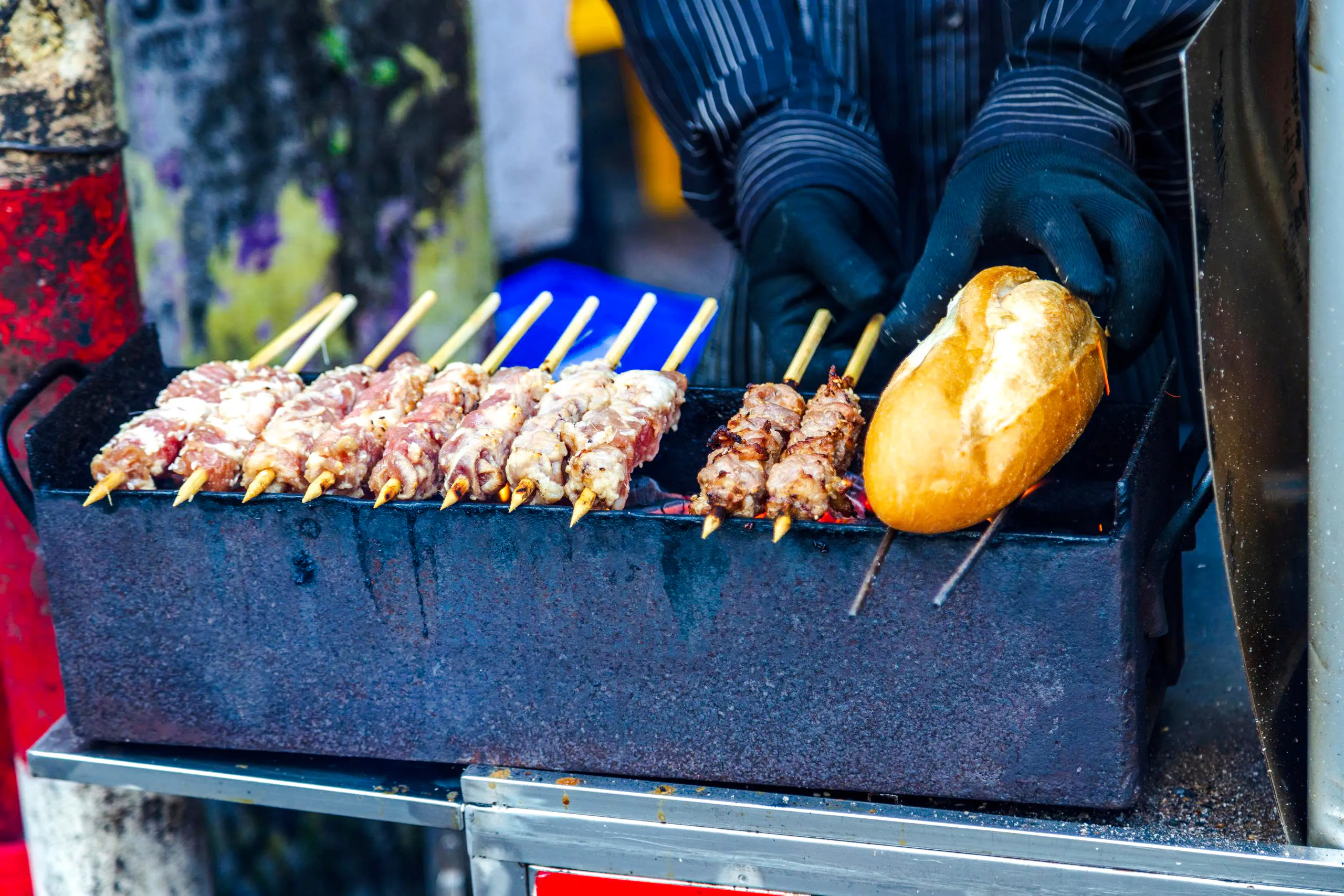 Grilled meat skewers and bread on a street food grill in Ho Chi Minh City.