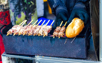 Grilled meat skewers and bread on a street food grill in Ho Chi Minh City.