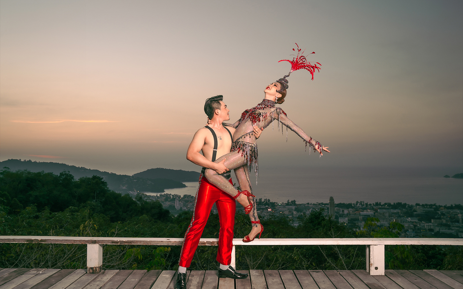 Performers in vibrant costumes at Simon Cabaret Show, Phuket, with scenic backdrop.