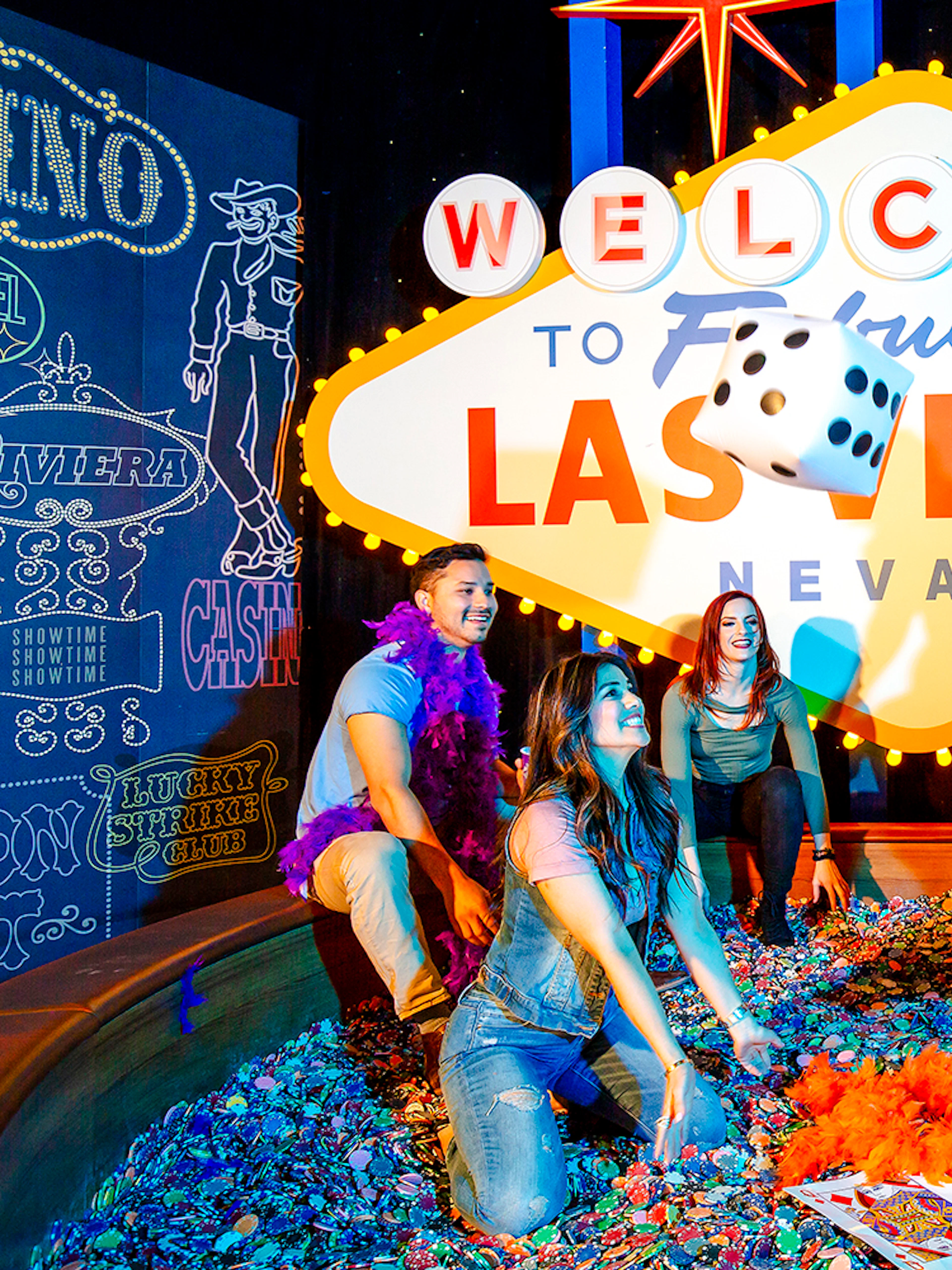 Guests enjoying interactive exhibit at Madame Tussauds Las Vegas with iconic sign and dice.