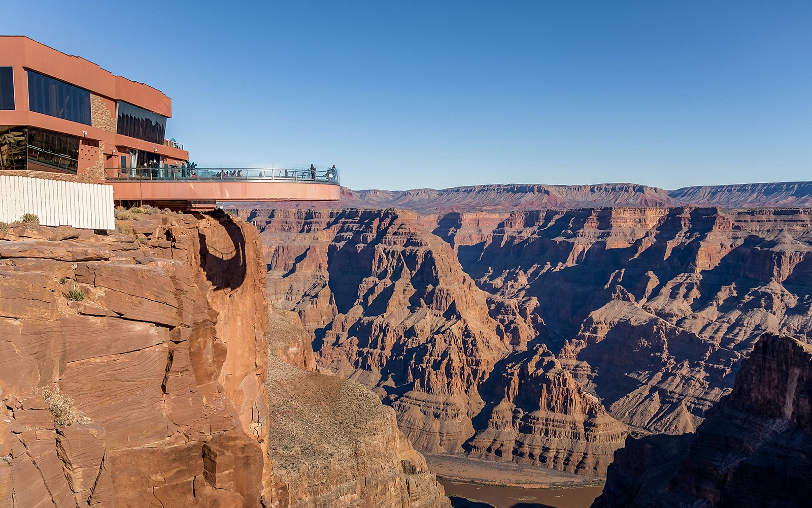 Tourists at Grand Canyon West overlook with Hoover Dam view on Las Vegas bus tour.