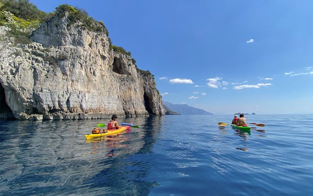 Kayakers paddling along the Sorrento Coast near rocky cliffs on a tour to Crapolla Fjord.