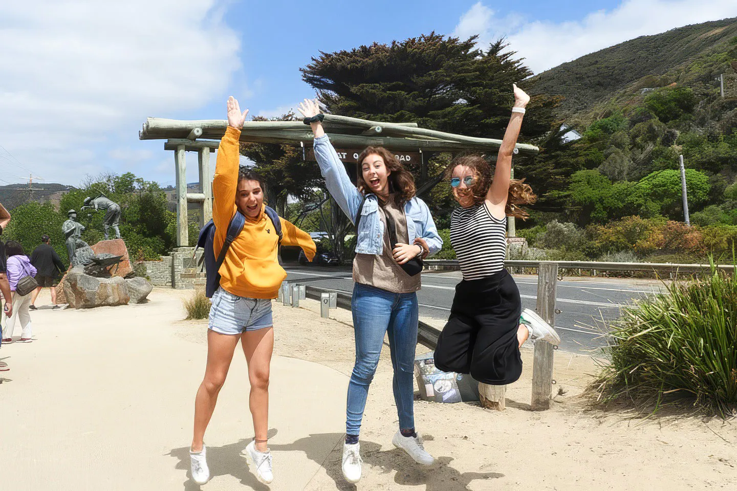 Tourists jumping at the Great Ocean Road entrance during Melbourne nature tour.