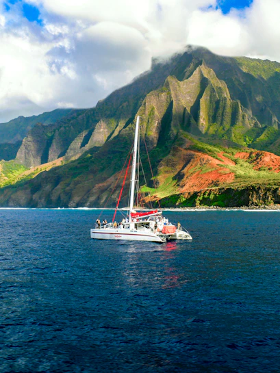 Catamaran sailing near the cliffs of Napali Coast, Hawaii.
