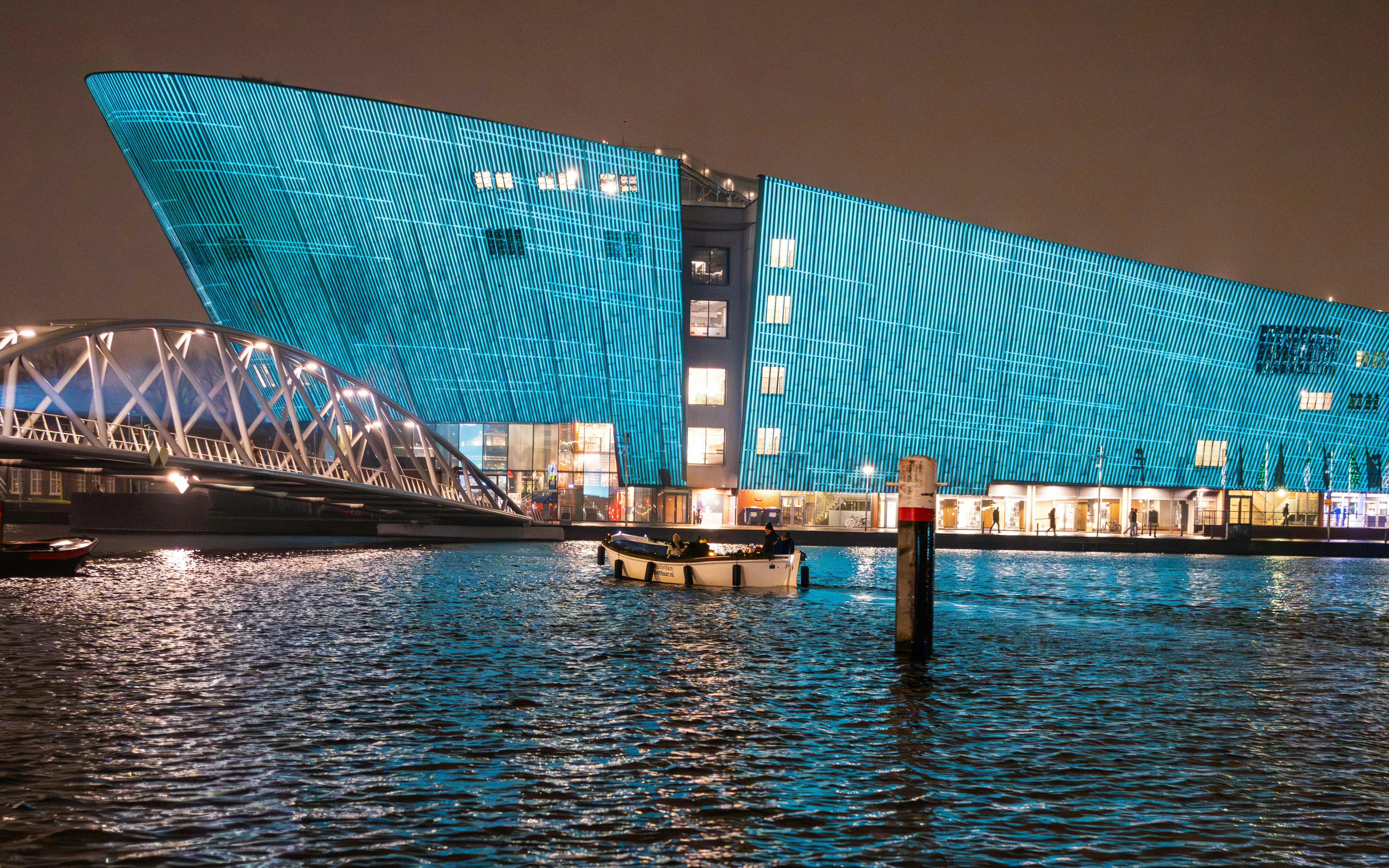 Amsterdam Light Festival, illuminated building and bridge over canal at night.