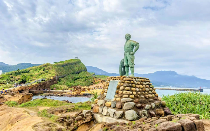 Statue of Lin Tianzhen at Yehliu Geopark, Taiwan, with coastal landscape.