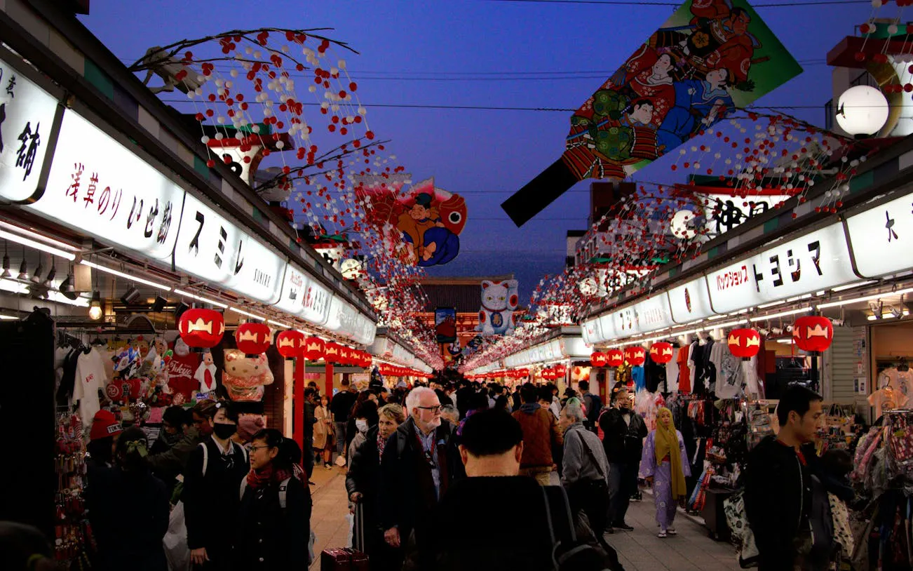 Crowded Nakamise Street in Asakusa, Tokyo, with shops and traditional decorations.