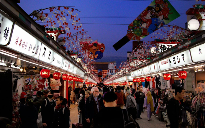 Crowded Nakamise Street in Asakusa, Tokyo, with shops and traditional decorations.