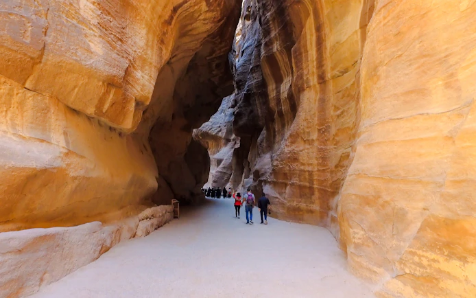 Tourists walking through the Siq canyon leading to Al Khazneh in Petra, Jordan.