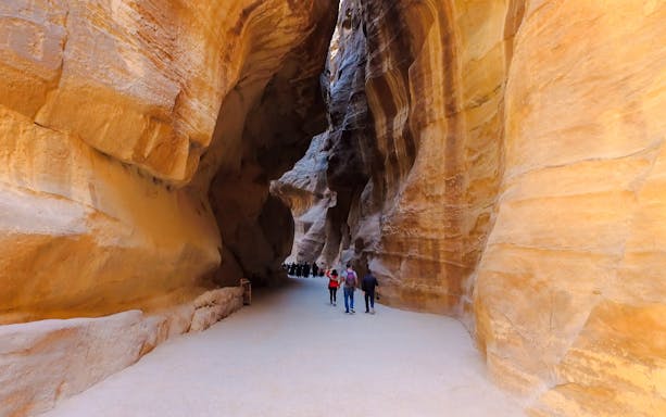 Tourists walking through the Siq canyon leading to Al Khazneh in Petra, Jordan.