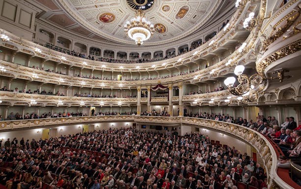 Interior view of the Semper Opera House in Dresden filled with an audience.