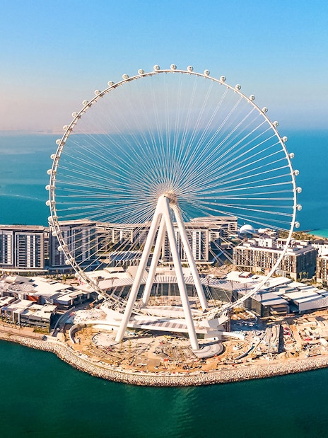 Ain Dubai Ferris wheel on Bluewaters Island, Dubai, UAE, with surrounding buildings and coastline.