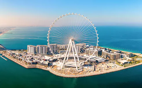 Ain Dubai Ferris wheel on Bluewaters Island, Dubai, UAE with surrounding buildings and coastline.