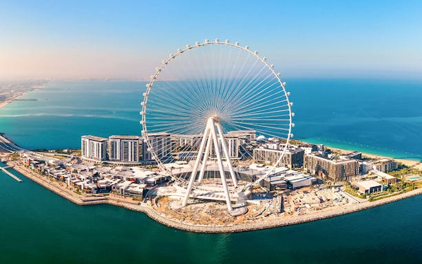 Ain Dubai Ferris wheel on Bluewaters Island, Dubai, UAE, with surrounding buildings and coastline.