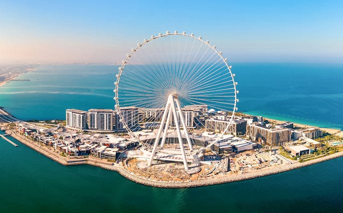 Ain Dubai Ferris wheel on Bluewaters Island, Dubai, UAE, with surrounding buildings and coastline.