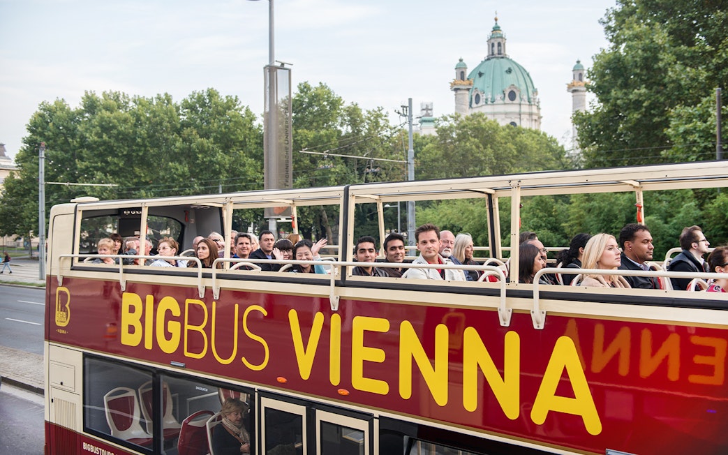 Tourists on Big Bus Vienna with St. Charles Church in the background.