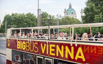 Tourists on Big Bus Vienna with St. Charles Church in the background.