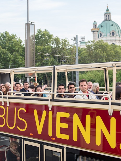 Tourists on Big Bus Vienna with St. Charles Church in the background.