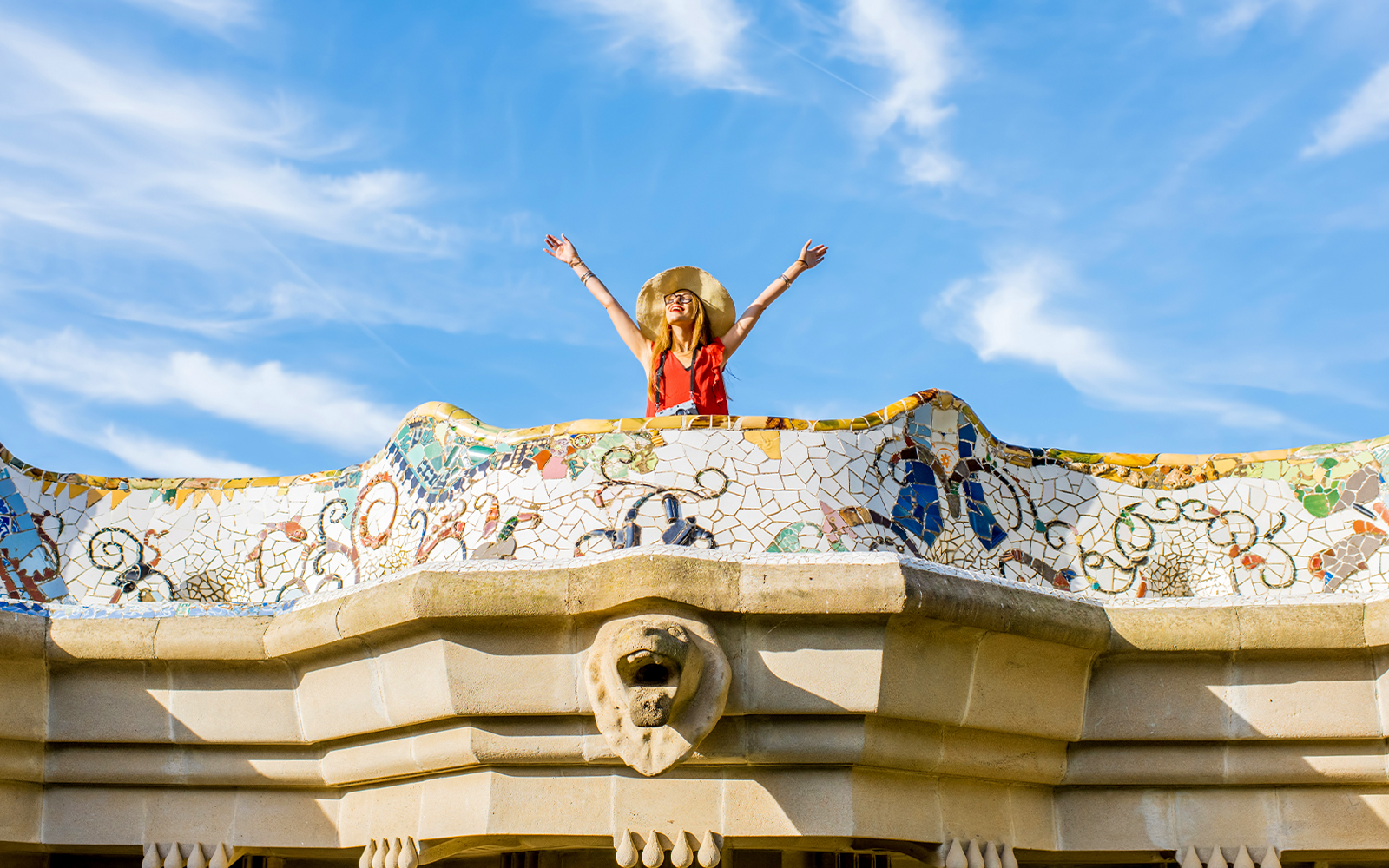 Women standing on colorful ceramic wall in Park Güell, Barcelona.