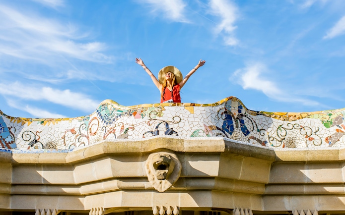 Women standing on colorful ceramic wall in Park Güell, Barcelona.