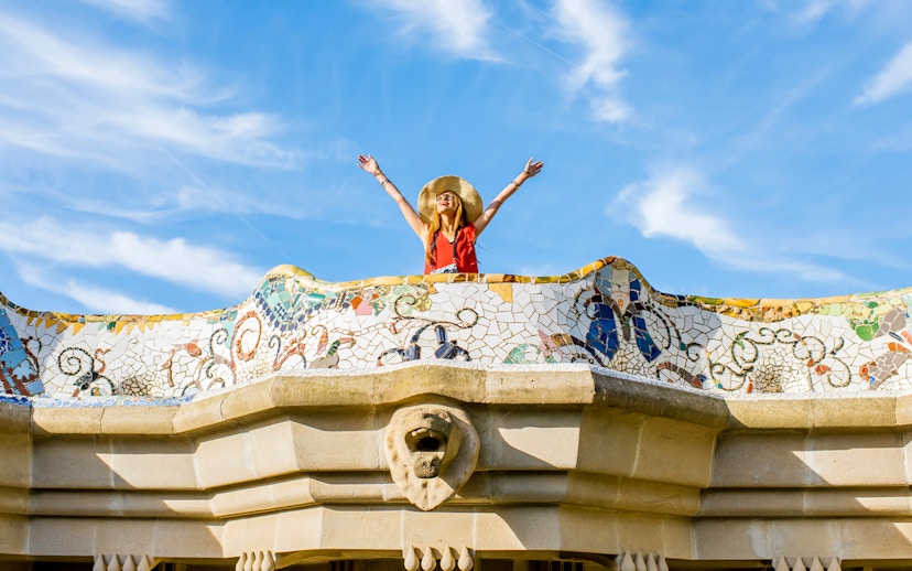 Women standing on colorful ceramic wall in Park Güell, Barcelona.