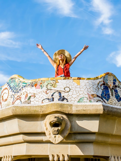 Women standing on colorful ceramic wall in Park Güell, Barcelona.