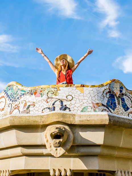 Women standing on colorful ceramic wall in Park Güell, Barcelona.