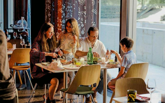 Family enjoying a meal at a restaurant table with pizza and drinks.