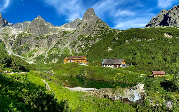 Slovakia Treetop Walk with mountain view and rustic cabins in lush green landscape.