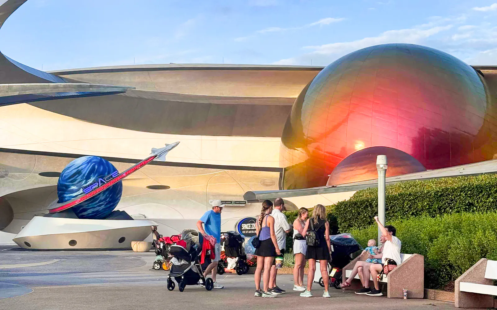 Visitors at Space Center, Walt Disney Resort Orlando, near futuristic architecture and space-themed decor.