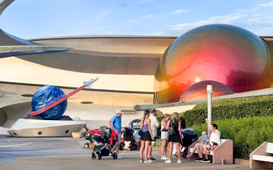 Visitors at Space Center, Walt Disney Resort Orlando, near futuristic architecture and space-themed decor.