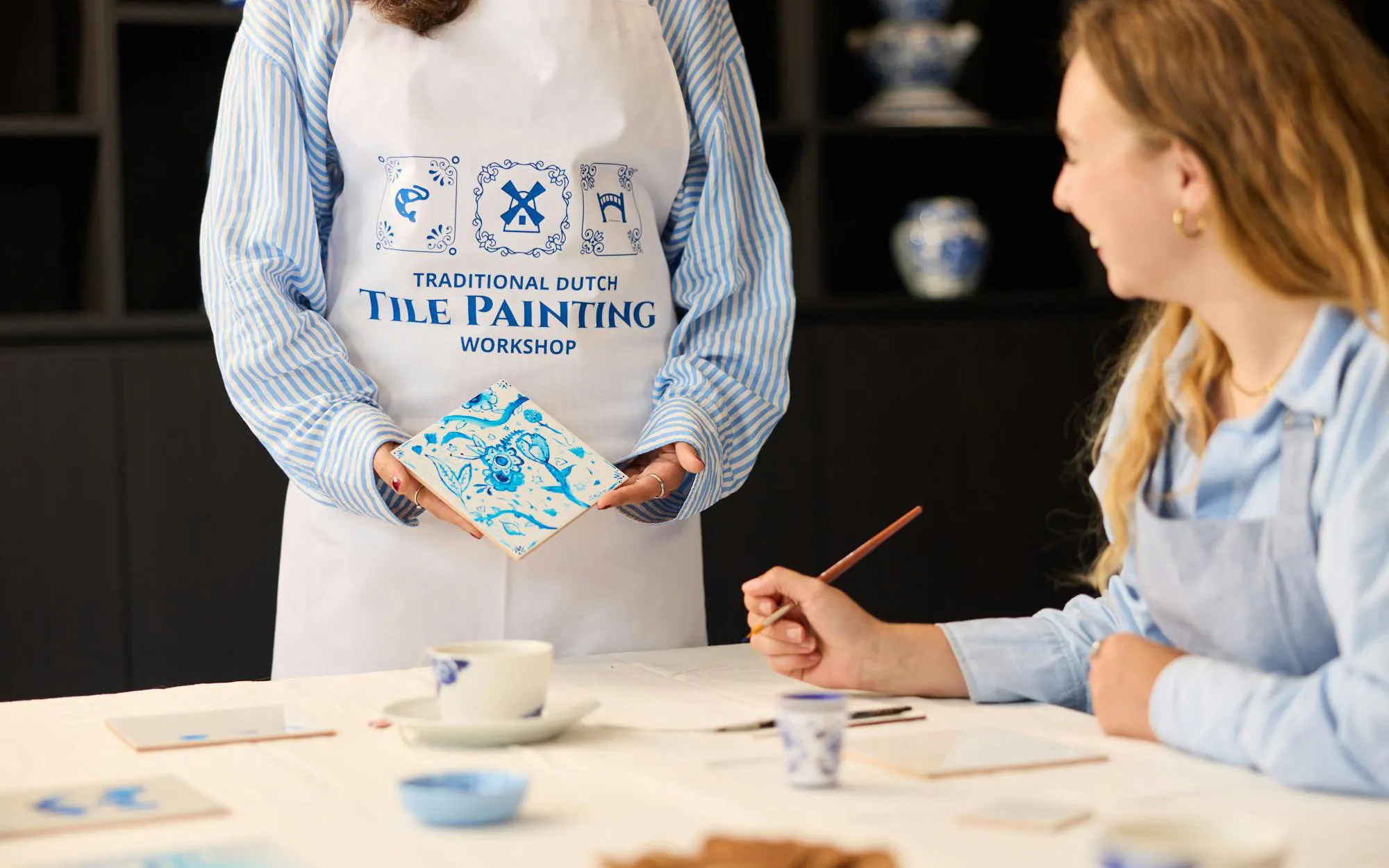 Guests participating in a Dutch blue tile painting workshop, creating traditional designs.