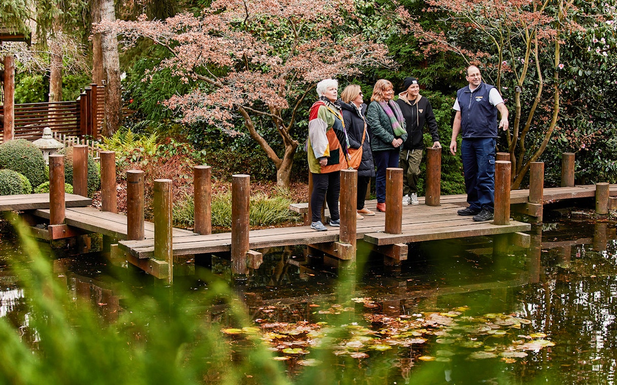 Group on a wooden bridge in a garden during Hobart city tour.